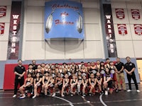 a group of wrestlers posing for a picture in a gym