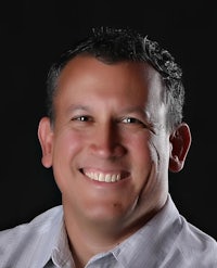 a man in a white shirt smiling for the camera